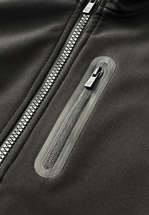 Zwarte gezipte jas met een gladde textuur en een contrasterende zak met rits met een transparante rand, naast een duurzame metalen hoofdrits.