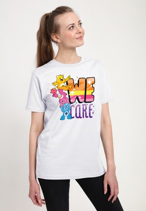 Hvid bomulds-T-shirt med farverige tegneseriebjørne og teksten "VI BEKYMREN" i fede, gradient bogstaver. Korte ærmer og afslappet pasform.