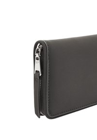 Czarny skórzany portfel o gładkiej fakturze, zamek błyskawiczny i srebrne akcenty hardware. Posiada smukły design z minimalną ilością szwów.