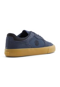 Zapatillas de skate azul marino con un upper de tela texturizada, suela de goma marrón claro y logo bordado en el lateral. Diseño de perfil bajo para mayor comodidad.