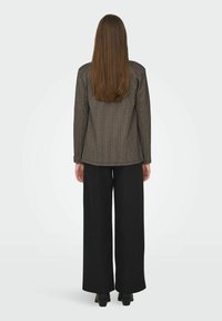 Brown checkered blazer with a tailored fit, paired with wide-leg black trousers. Smooth texture with long straight hair visible.