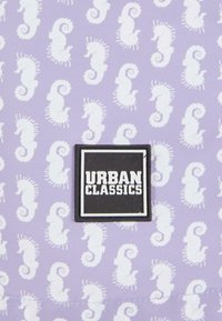 Lila szövet, fehér tengeri lovakkal díszítve; fekete négyzetes címke, rajta vastag fehér betűkkel "URBAN CLASSICS" felirattal.