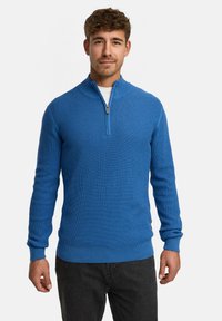 Blauer Strickpullover mit einem Viertel-Reißverschluss-Kragen, langen Ärmeln und gerippten Bündchen. Texturiertes Material mit einer taillierten Passform.