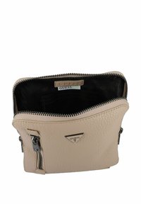 Borsa in pelle beige con superficie testurizzata e chiusura con zip. Dotata di accessori in argento e un interno nero con più tasche.