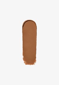 Brun kremfoundation swatch med en jevn tekstur. Oval form, rik farge, minimal glans, på en hvit bakgrunn.