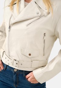 Weiße Leder-Bikerjacke mit Reißverschluss-Taschen, tailliertem Gürtel und diagonalen Revers mit silbernem Zubehör und detaillierter Naht.