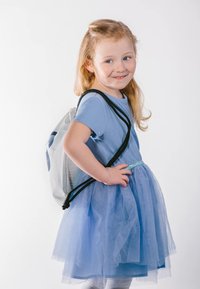 Šedý batoh na stažení s logem, nošený přes světle modré šaty s tylovou sukní. Dítě má světle blonďaté vlasy a stříbrné punčocháče.