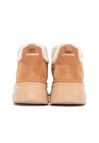 Brązowe zamszowe buty z beżowymi grubymi podeszwami i białym futerkiem, widok z tyłu, z napisem "CRIME" na każdym zakładce na pięcie.