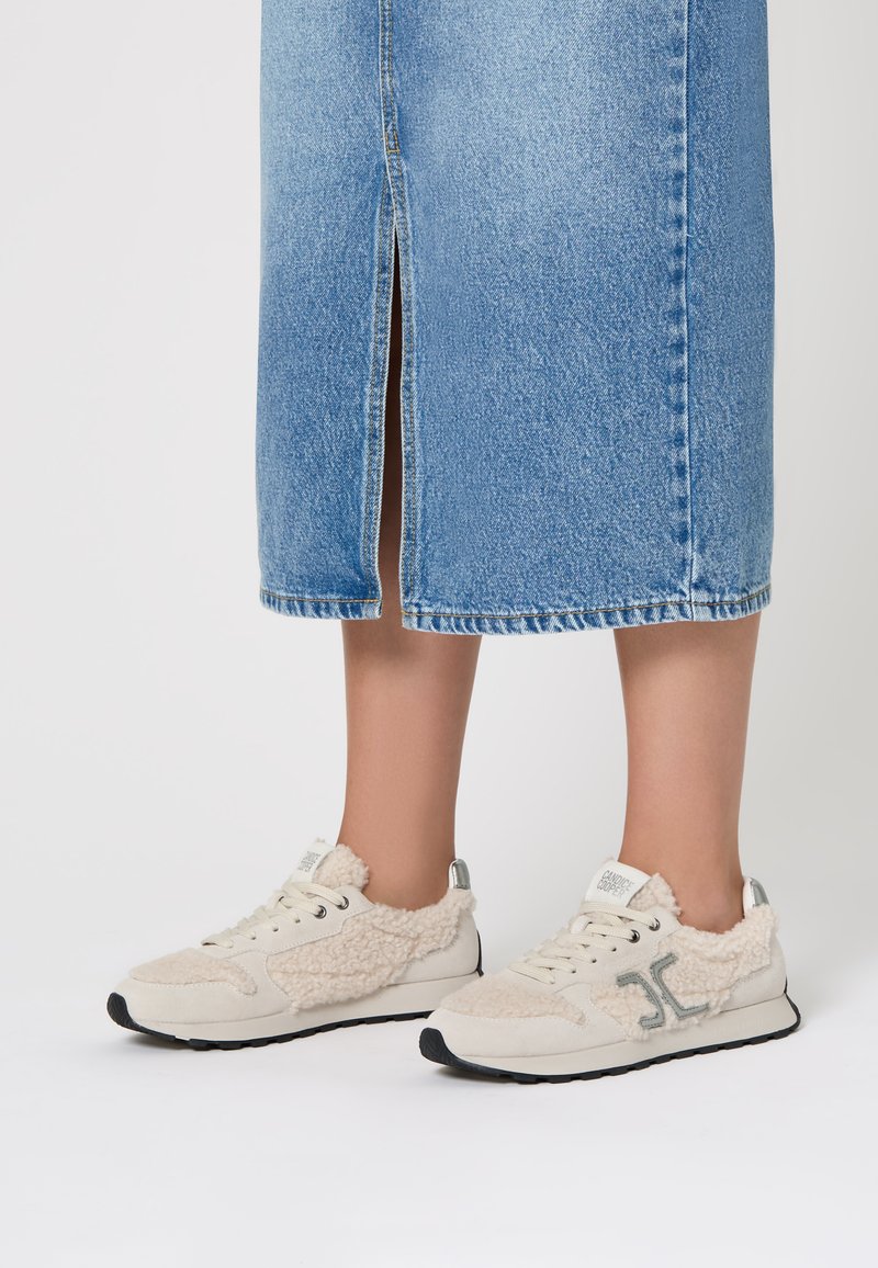 Sneaker beige con dettagli in pelliccia texure, lacci bianchi e logo grigio. Suola in gomma, materiale morbido e design della punta arrotondato.