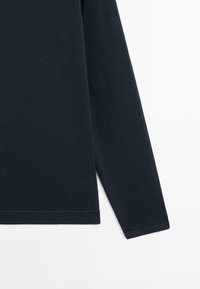 Dunkelblaue Strickbluse mit langen Ärmeln und geradem Saum, flach auf weißem Hintergrund präsentiert.