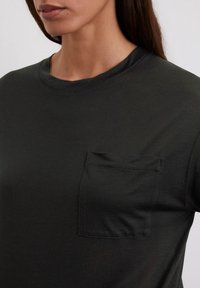 Zwarte katoenen t-shirt met een ronde hals en korte mouwen, voorzien van een patch pocket op de linker borst en een gladde, iets gestructureerde afwerking.