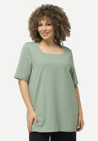 T-shirt verde chiaro con scollatura quadrata e maniche corte. Realizzato in tessuto morbido; vestibilità ampia con bordo inferiore curvo.