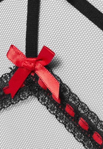 Μαύρη δαντέλα με κόκκινη κορδέλα υφασμένη μέσα και ένα κόκκινο σατέν φιόγκο σε φόντο από λεπτό υφαντό εξαγωνικό δίχτυ.