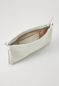 Borsa a mano bianca realizzata in tessuto testurizzato, dotata di una zip superiore e di una tasca interna con scomparti per carte. Fodera liscia.