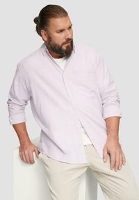 Lichtroze knoopshirts met opgerolde mouwen, gestructureerde stof en een borstzak, gecombineerd met beige corduroybroeken.