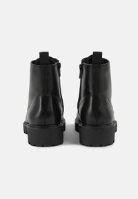 Stivali ankle in pelle nera con una texture liscia, punta arrotondata, suola in gomma spessa e doppie cerniere laterali per una facile vestibilità.