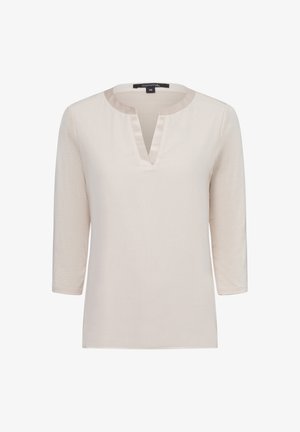 Camicetta beige chiaro a maniche lunghe con scollatura rotonda e un piccolo taglio a V frontale, realizzata in un tessuto liscio con minima trama.
