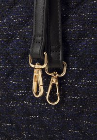 Zwart-blauwe geweven handtas met gouden hardware, lederen banden en kreeftenhaken met getextureerde details.