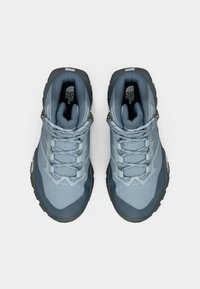 Plave sportske tenisice s teksturiranim gornjim dijelom, ojačanim prstima i kontrastnim tamnosivim potplatom. Imaju vezice za vezanje i podstavljeni ovratnik.