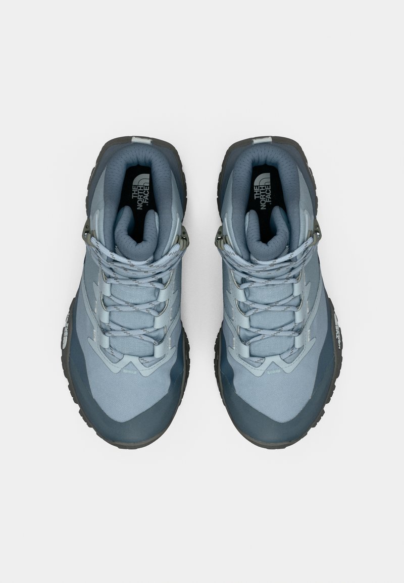 Blå atletiksko med en struktureret overdel, forstærket tå og kontrasterende mørkegrå sål. Har snørelukning og polstret krave.