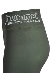 Zielone oliwkowe legginsy sportowe z wysokim stanem. Posiadają białe logo "hummel PERFORMANCE" z przodu i bezszwową strukturę.