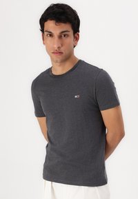 Tricou scurt cu mânecă, de culoare gri închis, confecționat din bumbac, cu un mic logo pe piept. Guler rotund, cu o croială standard.