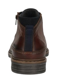 Bruine leren enkellaars met een zwarte stoffen hieltab, stikseldetails en een zwarte gestructureerde binnenvoering, van achter bekeken.