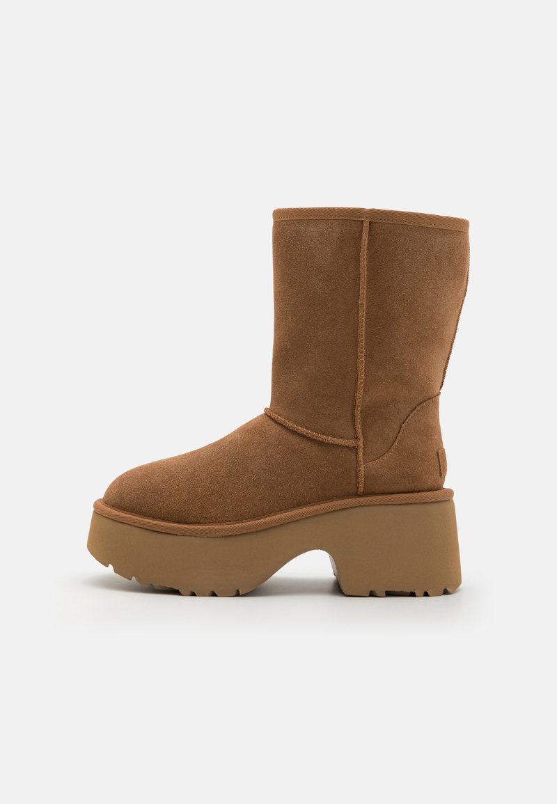 Bottine en daim marron à bout arrondi, dotée d'une semelle épaisse compensée et de coutures contrastantes. La bottine présente une texture lisse et un design épuré.