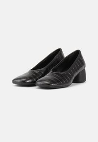 Pantofi negri din piele cu un model texturat de crocodil, vârf ascuțit și toc bloc de înălțime medie pentru stabilitate. Fodera interioară netedă.