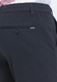 Shorts blu navy realizzati in tessuto leggero, dotati di una tasca posteriore con chiusura a bottone e un dettaglio di tessuto a righe all'interno della tasca.
