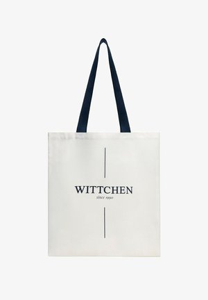 Bílá nákupní taška s černými držadly, s vertikálními liniemi a nápisem „WITTCHEN since 1990“ uprostřed na přední straně.