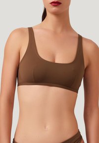 Reggiseno sportivo marrone, senza cuciture, con scollatura quadrata, spalline larghe e design minimalista, realizzato in materiale liscio ed elastico.