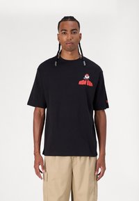 Μαύρο βαμβακερό t-shirt με άνετη εφαρμογή, με κόκκινα γράμματα "NEW ERA" και ένα γραφικό σχέδιο στο αριστερό στήθος. Κοντά μανίκια, ελάχιστη υφή.