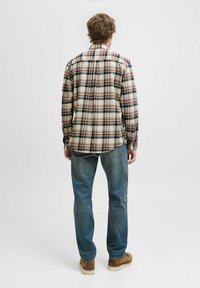 Geruite flanellen overhemd in beige, bruin en marine kleuren, met lange mouwen, rechte snit en rugpas, gecombineerd met blauwe spijkerbroeken.