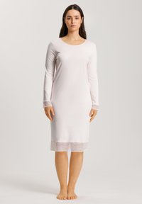 Camicia da notte a maniche lunghe di colore rosa chiaro, realizzata in tessuto morbido, con scollatura tonda e orlo trasparente con dettaglio a motivo.