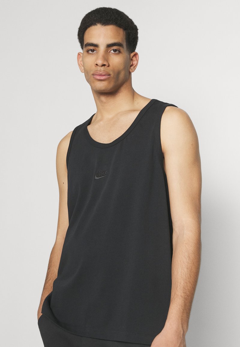 Camiseta sin mangas de algodón negro con un escote redondo, que presenta un sutil logo de Nike en el pecho. Diseño ligero y casual.