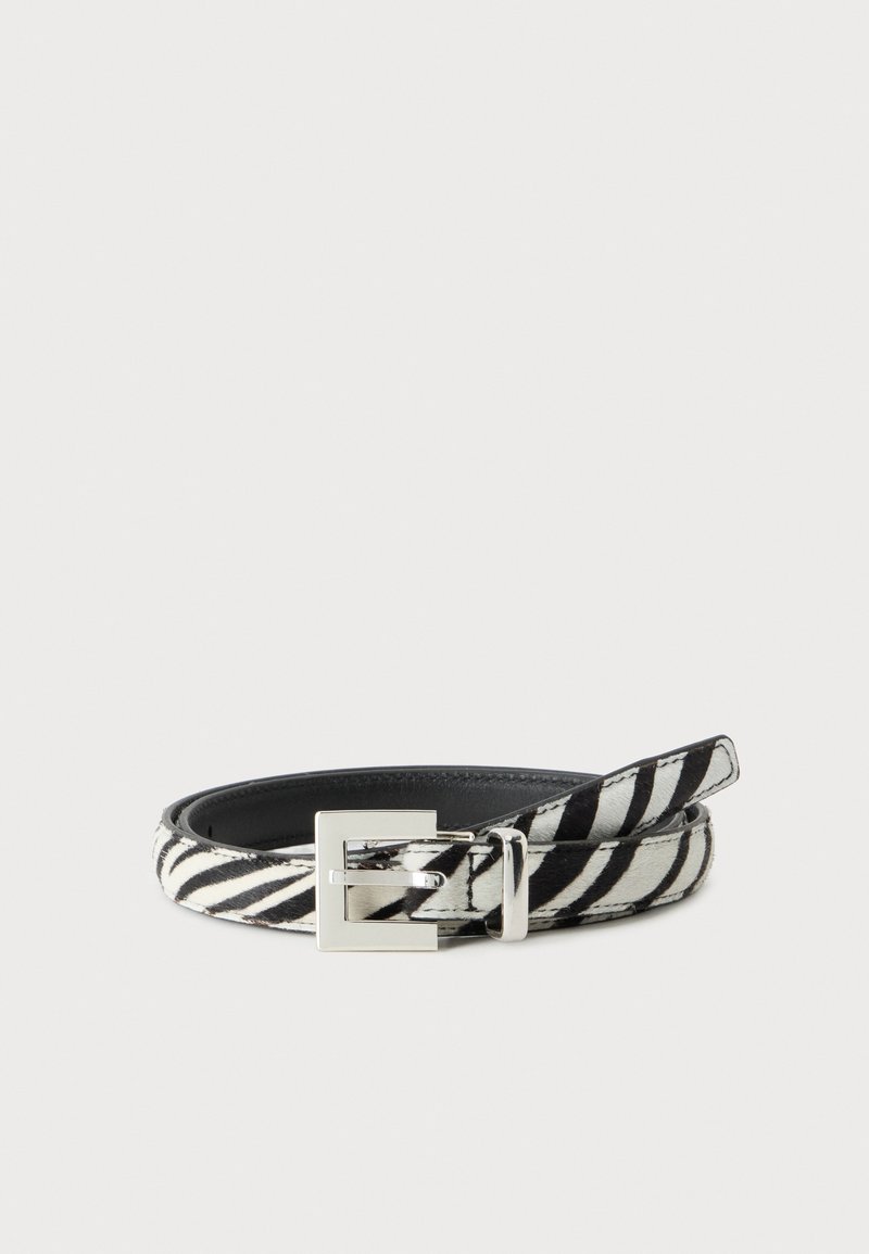Ceinture en cuir imprimée zèbre noir et blanc avec une boucle rectangulaire argentée, enroulée sur un fond clair uni.