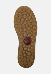 Brun gummisula med texturerade cirkulära mönster, en upphöjd cirkulär logotyp i burgundy och storleksmarkeringar. Rund form med slät kant.