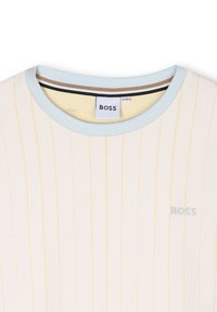 Crème shirt met lichtgele verticale strepen, ronde lichtblauwe halslijn en klein geborduurd "BOSS" logo in lichtblauw.