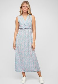 Maxime dress in light blue with pink abstract pattern, sleeveless design, v-neckline, gathered waist, soft texture, paired with white sneakers.