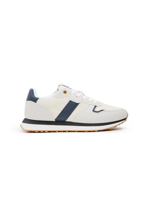 Zapatilla blanca con detalles en azul marino, materiales de lona y goma, puntera redondeada, diseño con cordones y suela texturizada para mayor agarre.