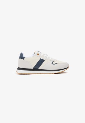 Zapatilla blanca con detalles en azul marino, materiales de lona y goma, puntera redondeada, diseño con cordones y suela texturizada para mayor agarre.