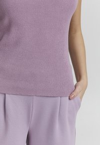 Ljuslila ribbat stickad ärmlös topp med en figurnära design och bred rundad halsringning, kombinerad med matchande plisserade lavendelfärgade byxor.