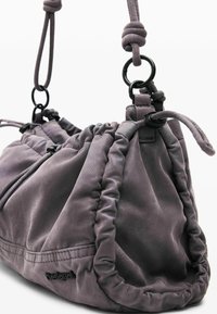 Siva kožna torba s naboranim zatvaranjem i podešivim remenom. Sadrži crne metalne akcentne detalje i meku, teksturiranu površinu.