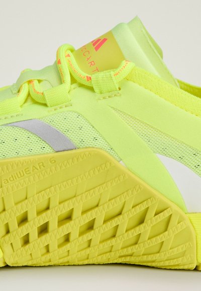Neon yellow athletic shoe with a mesh design, gray accents, textured sole, and secure lace system. Features flexible, breathable material.