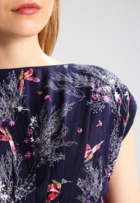 Navy blue dress with floral and bird patterns; lightweight fabric; pleated design; wide neckline and soft texture.