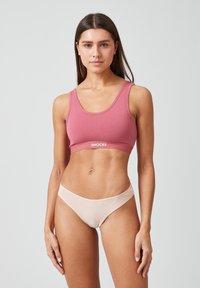 Różowy bawełniany stanik sportowy z szerokimi ramiączkami i logo na pasku, sparowany z cielistymi bawełnianymi majtkami typu bikini z gładkim pasem w talii.