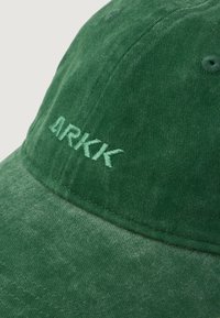 Cappello in cotone verde con logo in rilievo "ARKK" dello stesso verde, realizzato in tessuto testurizzato e con visiera curva.