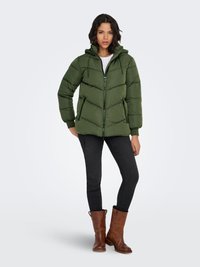 Žalia pūkinė striukė su gaubtu, užtrauktuko uždarymu ir ševrono siuvimu. Derinama su juodais siaurais džinsais ir rudu auliniu batais su kulnu.