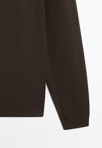 Dark brown long-sleeve knit sweater sleeve and hem with ribbed cuffs and bottom edge against a white background.